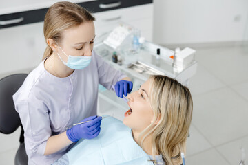 Dentist examining patient teeth with dental tools in clinic