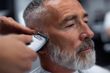 A man is getting his beard cut by a barber