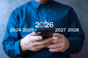 Businessman using smartphone with future target 2026 showing goal planning and digital business vision