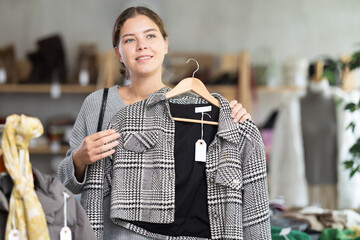 Female shopper selects clothes for autumn winter season in a clothing store