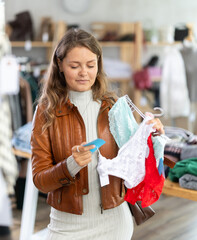 Positive young girl choosing pretty new panties in big lingerie store