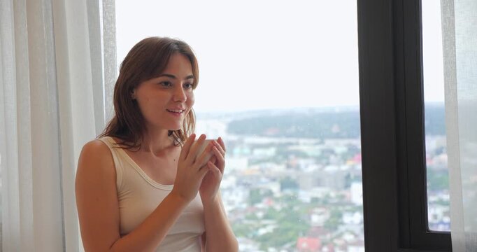A refreshed young woman joyfully smells her aromatic cup of coffee, ready to start a beautiful and productive morning
