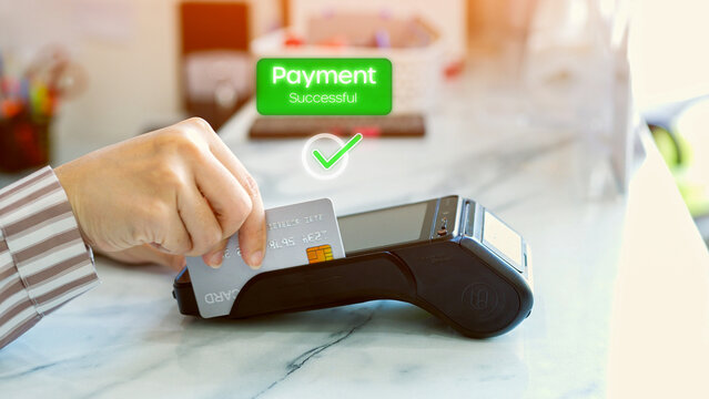 Close-up of customer's hand making payment by tapping credit card. The screen displays the message "Payment completed", a fast, secure and convenient financial transaction in a cashless society.