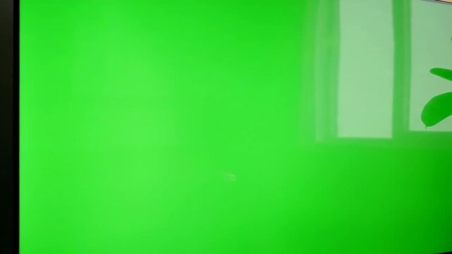 A modern television with a green screen in a living room. Slow zoom-in on a chroma key display for content mockups. Home entertainment and technology concept