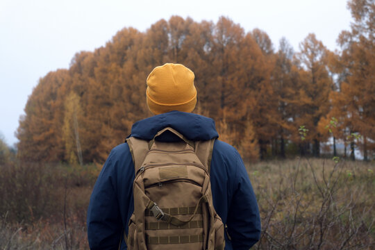 Man in the yellow hat hiking experiencing solitude in autumn forest