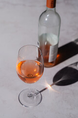 Close up of glass of rose wine and bottle on gray background.