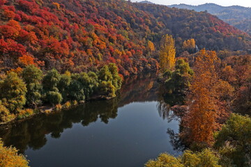 Fototapeta premium Soldier Lake. An urban lake surrounded by mountains with different vegetation. Autumn time, view from the drone.