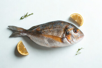 Fresh whole fish with lemon and herbs on white background