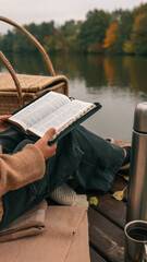 Reading the Bible by a lake on a peaceful autumn day