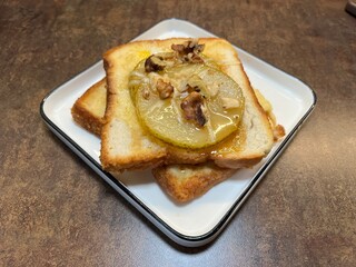 Delicious toast topped with caramelized pear slices and chopped nuts, served on a white plate. Ideal for food blogs, breakfast concepts