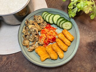 Asian-style lunch plate with rice, fried tofu, chili sauce, cucumber, and vegetables. Great for healthy lunch, vegan food, and homemade meal visuals