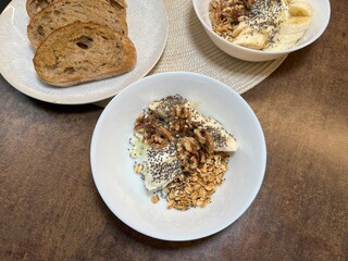 Breakfast bowl of yogurt topped with nuts and seeds served with sliced bread. Ideal for healthy lifestyle, morning meal, and diet visuals