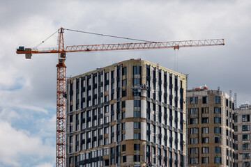 A Tower Crane Next To A Modern Multi-Storey Building Under Construction Against A Cloudy Sky, Representing Urban Development.