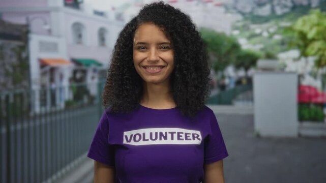 Smiling young woman volunteer in a purple shirt outdoors on a vibrant street illustrating community and youth engagement.