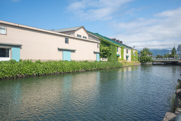 Historic warehouses along canal with greenery and blue sky in daytime at Hokkaido, Japan