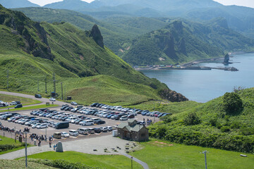 Tourists parking cars near green hills by the sea in a coastal landscape at Cape Kamui, Kozakicho, Hokkaido, Japan
