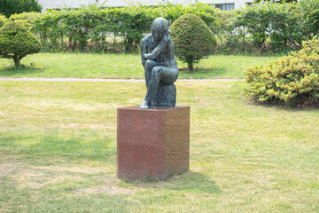 Bronze statue of a seated person in a public park garden at Lake Toya, Abuta, Hokkaido, Japan
