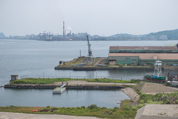 Industrial harbor with cranes and factory buildings near water, view from Hakucho Bridge, Hokkaido, Japan