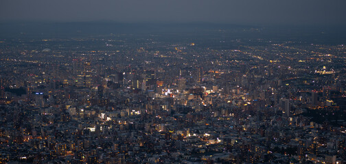 Panoramic view from Moiwa mountain, cityscape aerial view at dusk with illuminated buildings and streets at Sapporo, Hokkaido, Japan