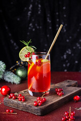 Christmas Sangria cocktail in glass and festive decor on dark table vertical photo, festive cranberry cocktail with lime