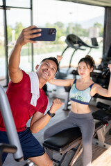 Fototapeta premium Fitness trainer coach man taking picture photo on phone with woman client after exercising in a gym