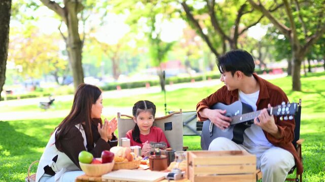 Happy parents and daughter Bakery and Bread Fruit enjoy  in a sunny garden. A joyful summer picnic full of love, food for family, outdoor, and lifestyle concepts.
