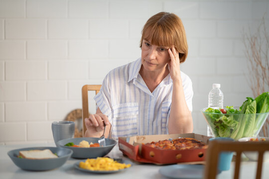 Elderly retired grandmother stay at home with painful face sitting alone on eating table in house. Depressed mature senior old woman upset feeling unhappy. Lonely and missing his family at home	