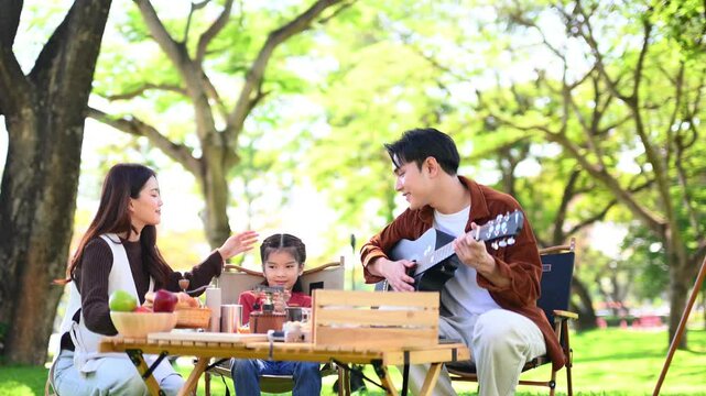 Happy parents and daughter Bakery and Bread Fruit enjoy  in a sunny garden. A joyful summer picnic full of love, food for family, outdoor, and lifestyle concepts.