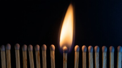 Dramatic close up of a single burning match with bright flame against dark background