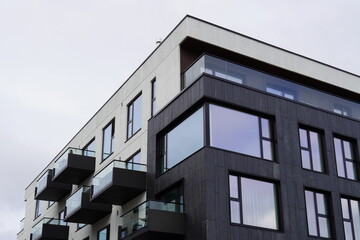 Modern apartment building with balconies and large windows under a cloudy sky in an urban setting
