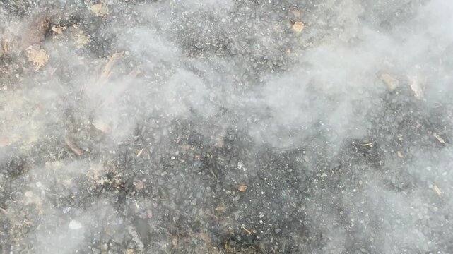 White Smoke Billowing Across Gravel Ground in Daylight