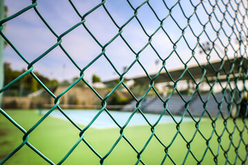 Fototapeta premium Close Up Green Painted Chainlink Fence In Front of Tennis Court