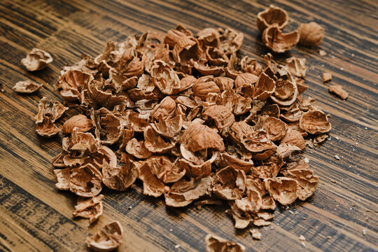 Pile of brown nutshells scattered on wooden surface during snack time at home