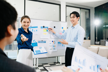 Fototapeta premium Smiling Asian business team shaking hands after successful meeting, symbolizing partnership, teamwork, and corporate success in a modern office