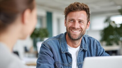Fototapeta premium Man and woman in office setting smiling at each other.