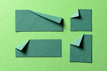 Pieces of blank paper notes or sheets with folded edge dog-ear earmark and copy space for text on green background, top view flat lay