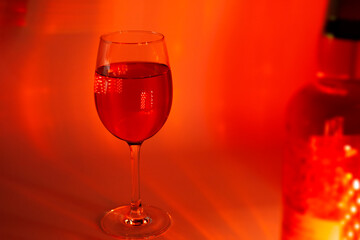 A single glass of red wine glowing in rich red lighting with soft reflections—perfect for holiday ads, romantic brochures, New Year’s celebrations, or luxurious seasonal wine promotions.