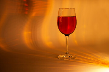A single glass of red wine glowing in rich red lighting with soft reflections—perfect for holiday ads, romantic brochures, New Year’s celebrations, or luxurious seasonal wine promotions.