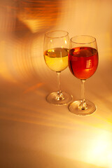 Two elegant wine glasses filled with red and white wine, glowing in golden light—perfect for Christmas dinners, festive brochures, seasonal advertising, or holiday celebration campaigns.