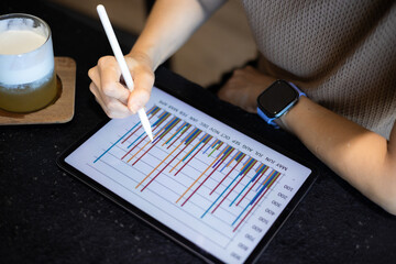Close-up of a woman working on a tablet while sitting at a coffee shop.