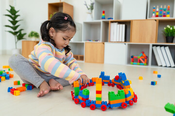 toddler girl playing building blocks or plastic bricks toy at home