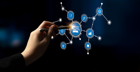 A close-up view of a hand holding a stylus, engaging with a digital network of icons that symbolize...