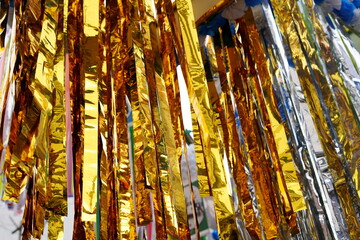 上部から垂れ下がる七夕飾りのメタリックな光沢を持つ金色の紙テープと銀色の紙テープが対照的な抽象的な背景