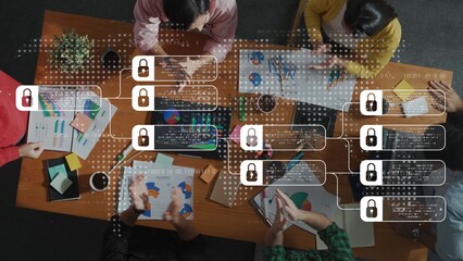A top-down view of a diverse group engaged in collaborative data analysis with visual charts on a table, emphasizing teamwork and secured information sharing in a modern workplace. Raster