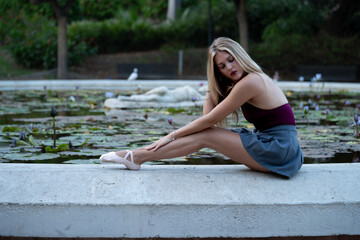 Ballerina posing gracefully by a lily pond outdoors