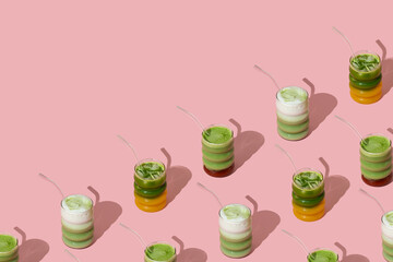 Creative pattern made with various colorful matcha drinks on pastel pink background with copy space. Minimal healthy matcha tea concept. Trendy drink idea.