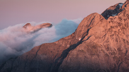 View of rugged mountain peaks emerge through a sea of clouds, kissed by the warm hues of the setting sun, creating a serene spectacle, Carrara, Tuscany, Italy.