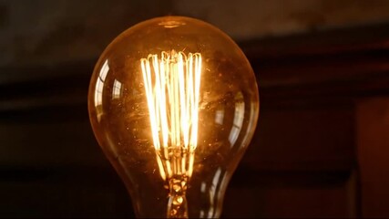 Close-up of a vintage Edison light bulb glowing in the dark. The camera focuses on the intricate incandescent filament. Idea, innovation, and energy concept - Powered by Adobe