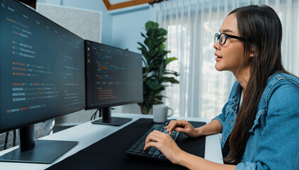 Young Asian in IT developer creating with typing online information on pc with coding program data of website application, wearing jeans shirt. surrounded by safety analysis two screens. Stratagem.