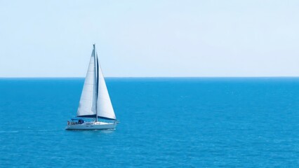 Fototapeta premium A sailboat sails on the blue sea, contrasting with the clear blue sky, fully showing the freedom of marine sports and the tranquil beauty of natural scenery. 